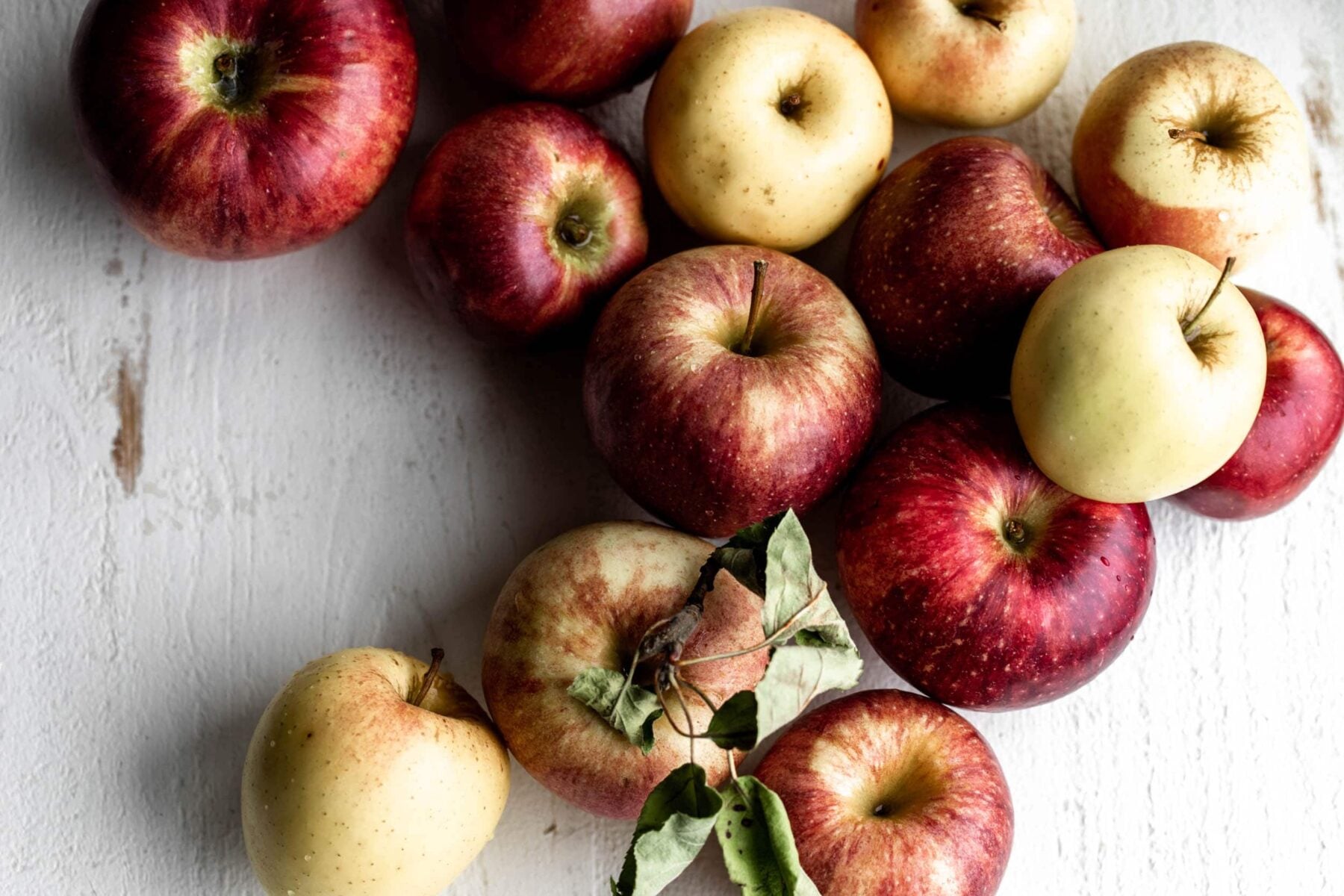 selection of fall apples arranged on white wood board.