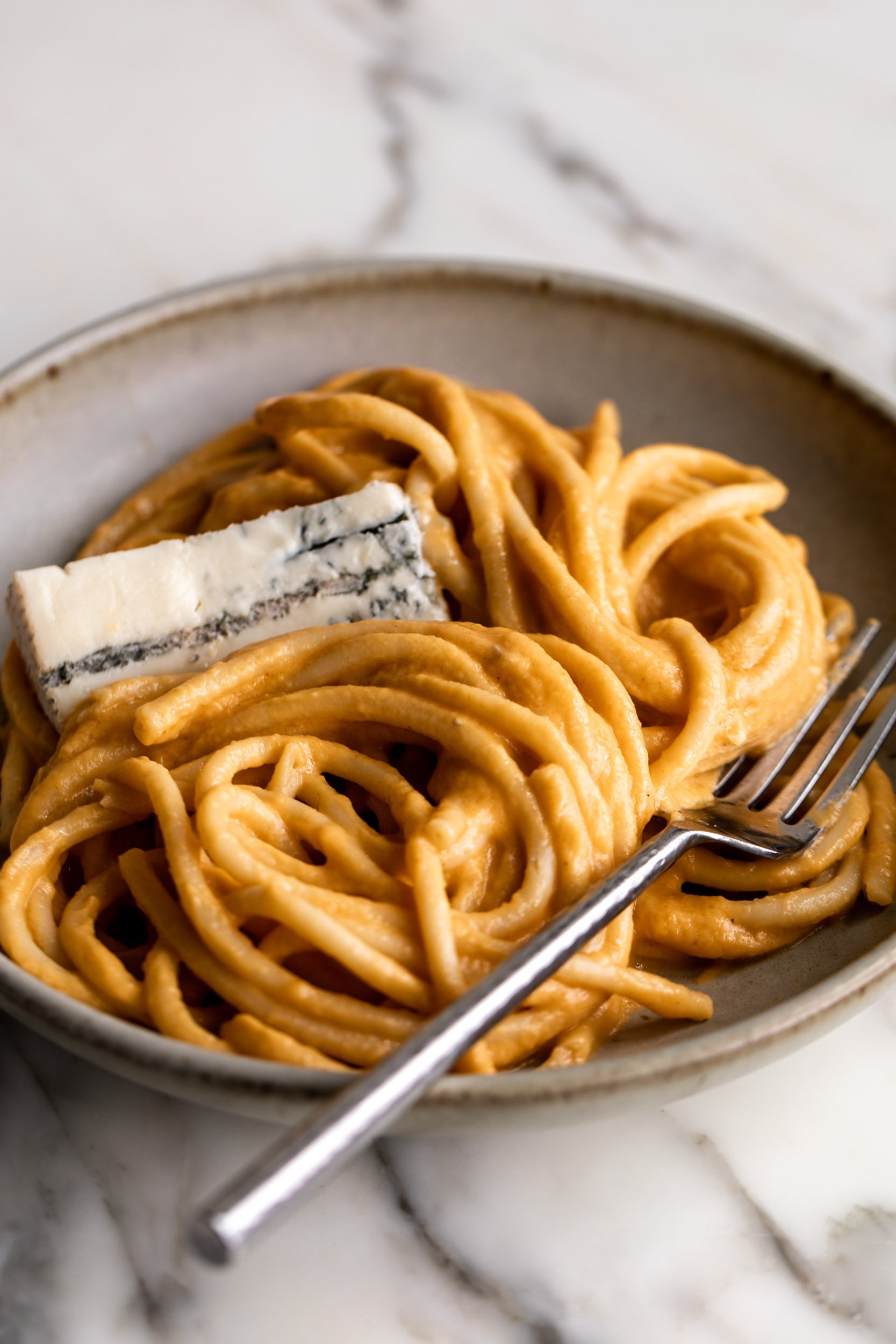 Creamy Pumpkin Pasta with Gorgonzola slices and fork.