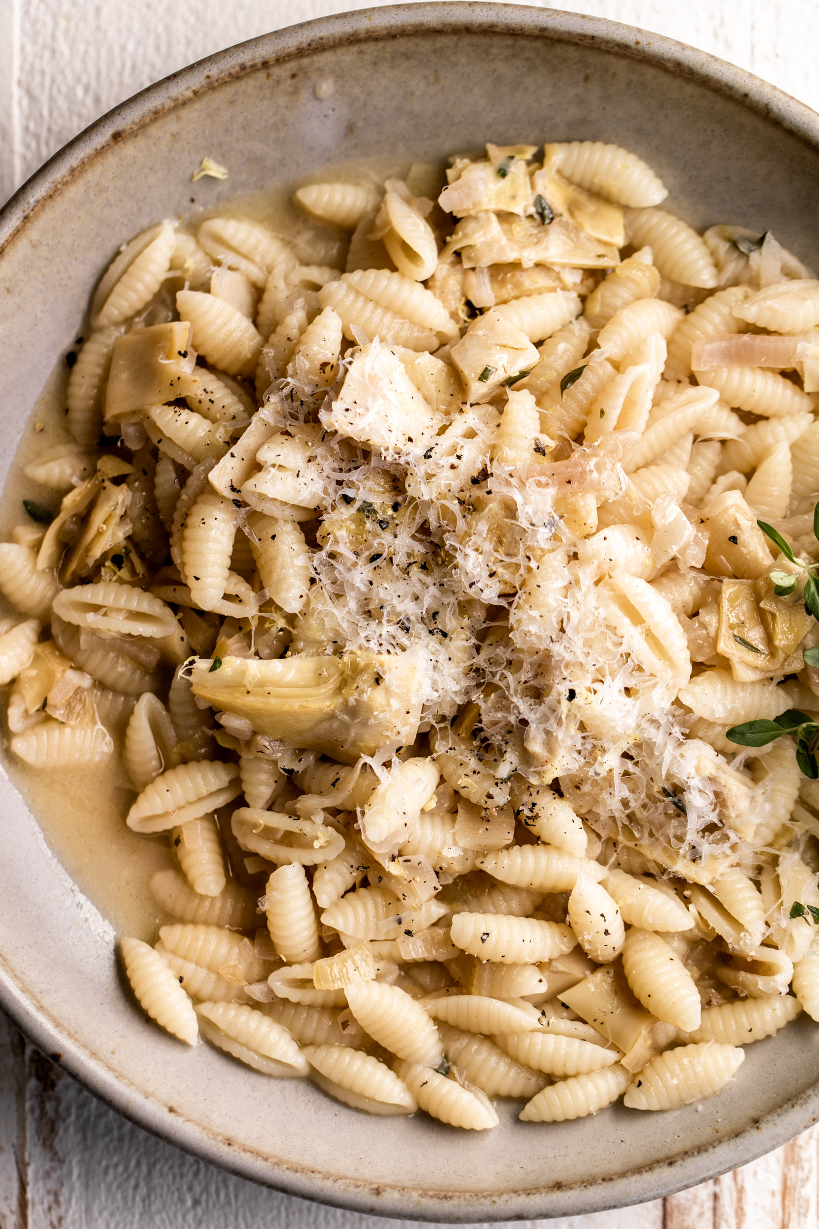 closeup lemon artichoke cavatelli pasta dish with parmesan cheese.