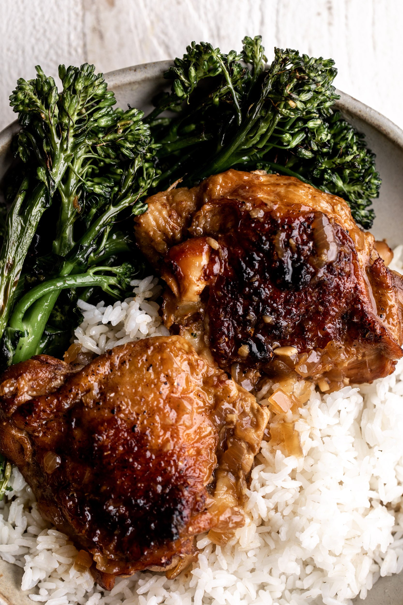 thighs with browned skin over rice with broccolini.