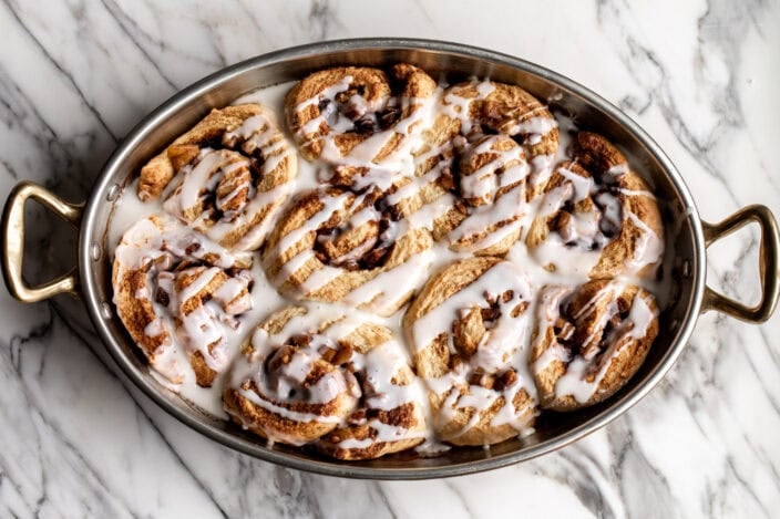 apple cinnamon rolls with icing in a oval baking dish.