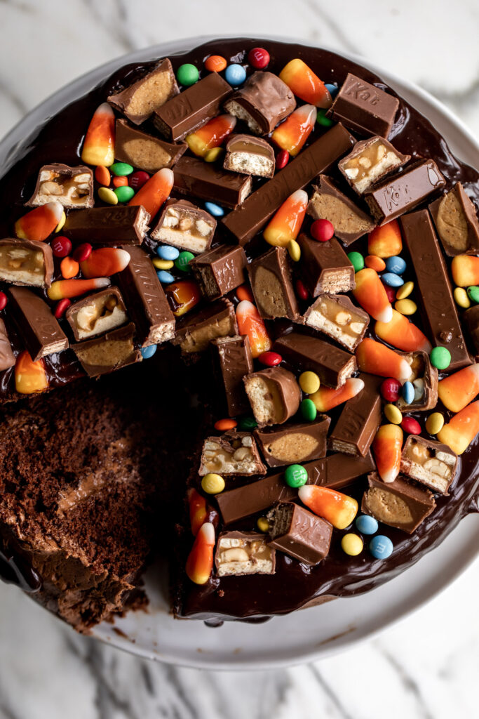 Chocolate Cake with Chocolate Ganache & Halloween Candy overhead with slice cut