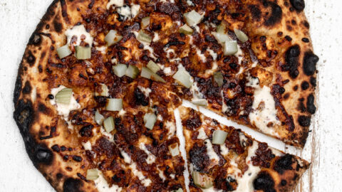 nashville hot chicken pizza topped with fried chicken a drizzle of alabama white sauce with chopped pickles