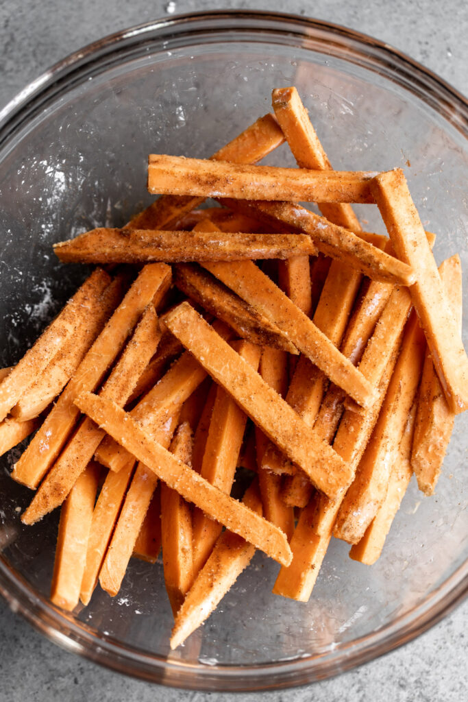 Baked Cinnamon Sugar Sweet Potato Fries in mixing bowl