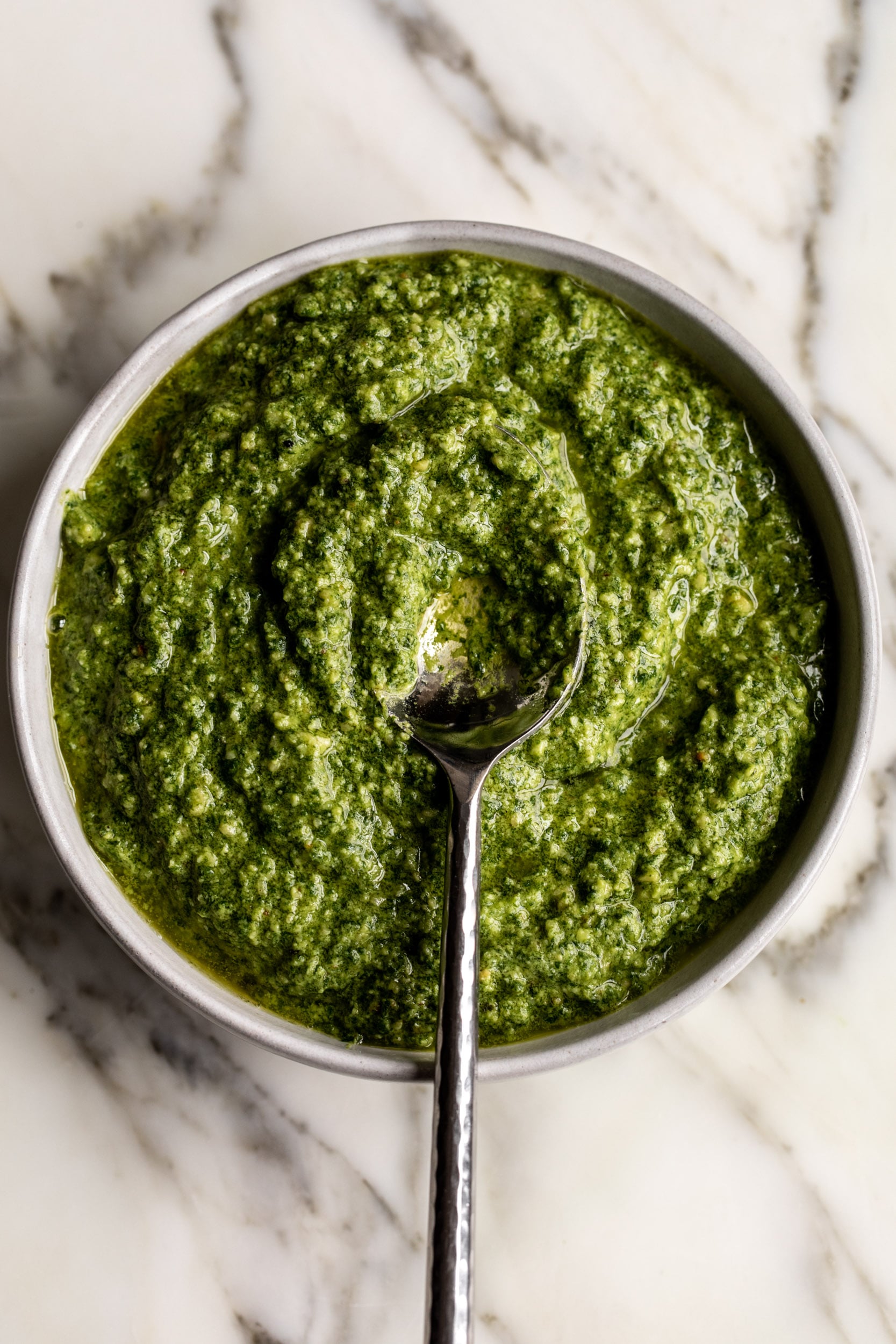 fresh blended pesto in bowl with spoon.