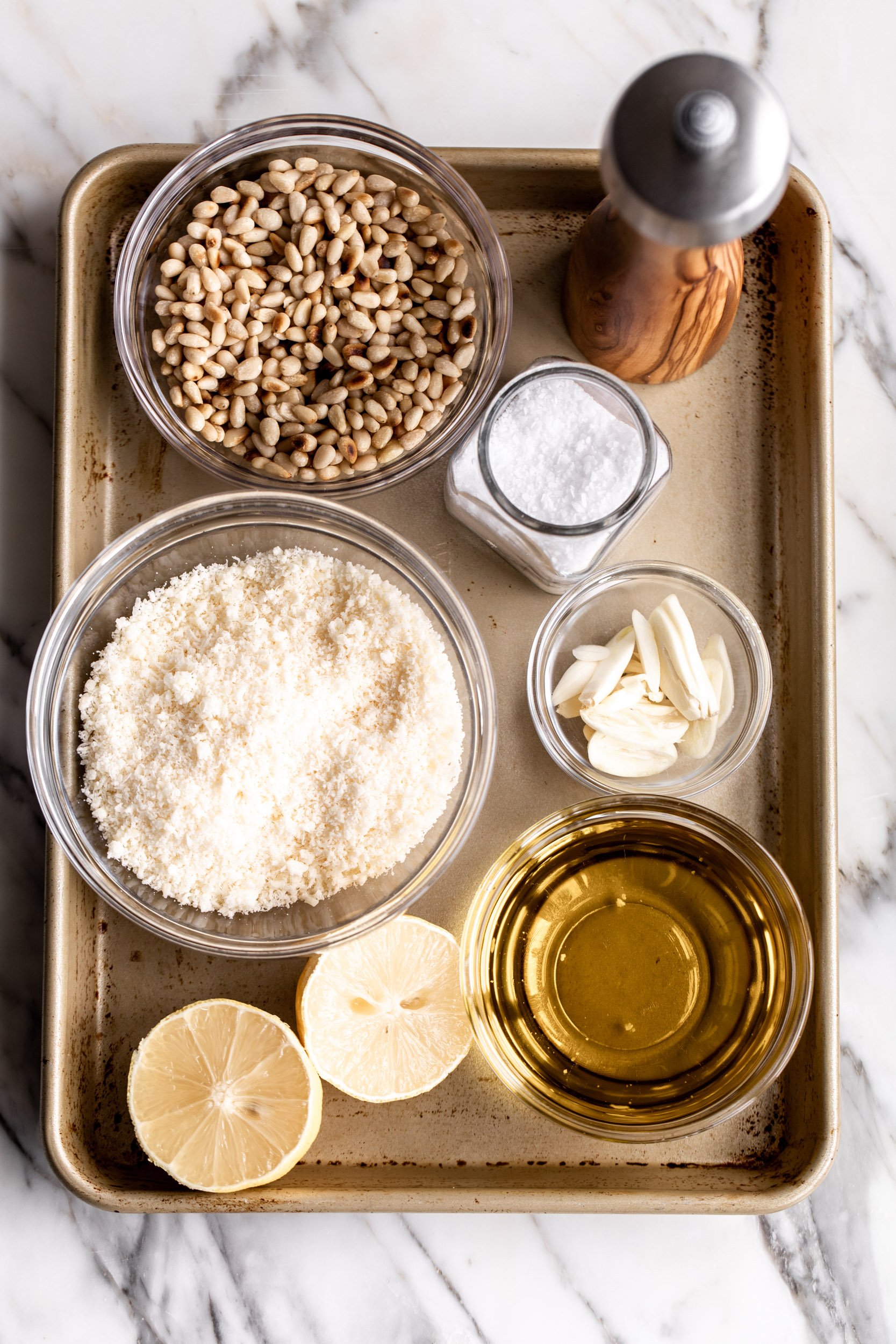 pesto ingredients with parmesan cheese and pine nuts on baking tray.