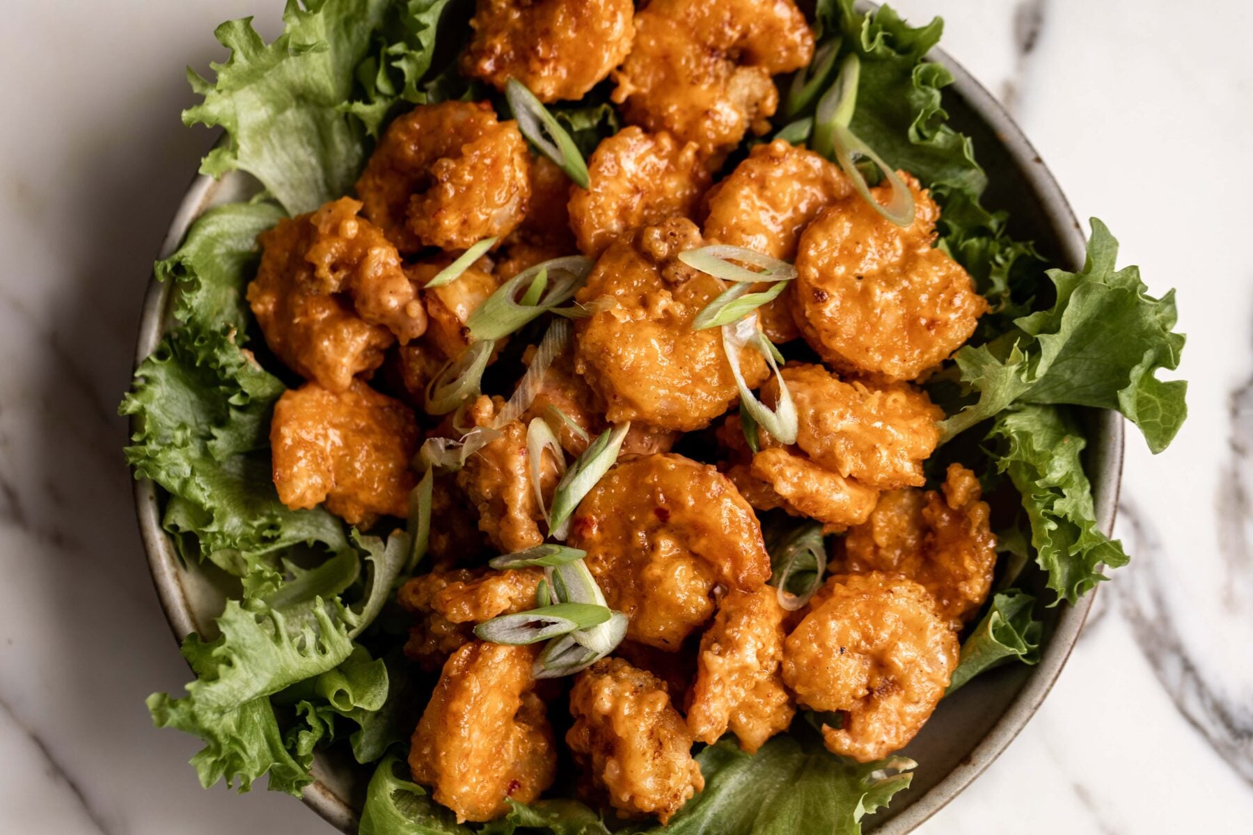 Bang Bang Shrimp Recipe over green leaf lettuce.