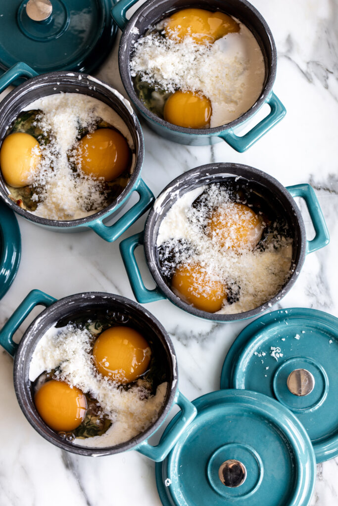 eggs en cocotte in mini cast iron pots prepared for oven.