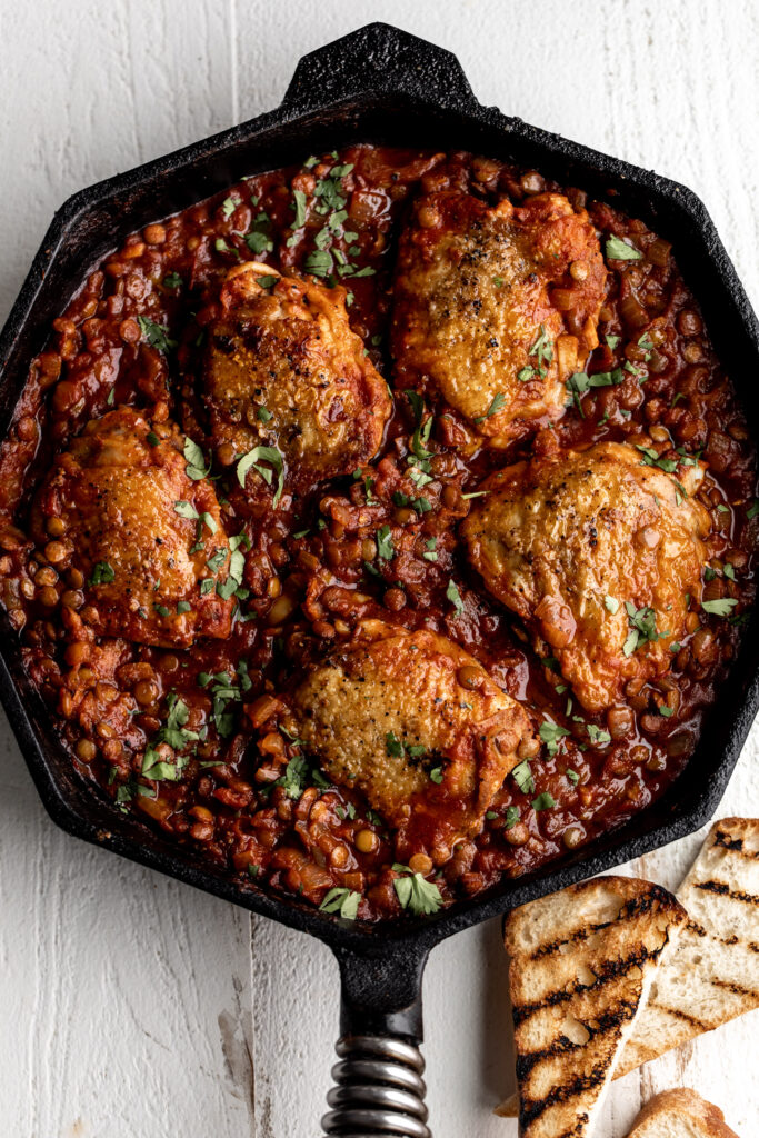 One-Pan seared Chicken Thighs with Harissa Lentils and tomatoes  with grilled bread