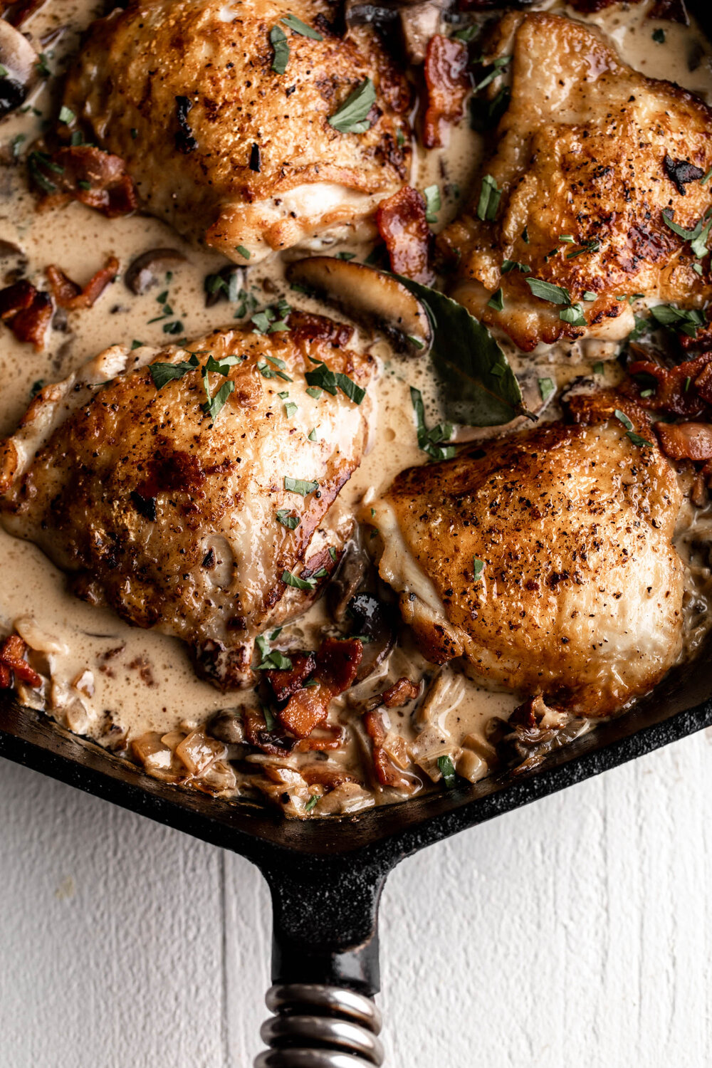 coq au vin blanc with bone in skin on thighs in creamy white sauce.