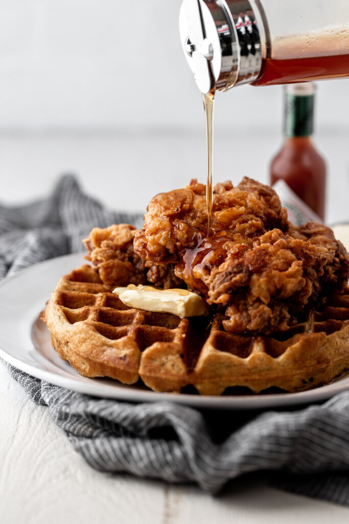 waffle topped with fried chicken pouring syrup over the top best chicken recipes