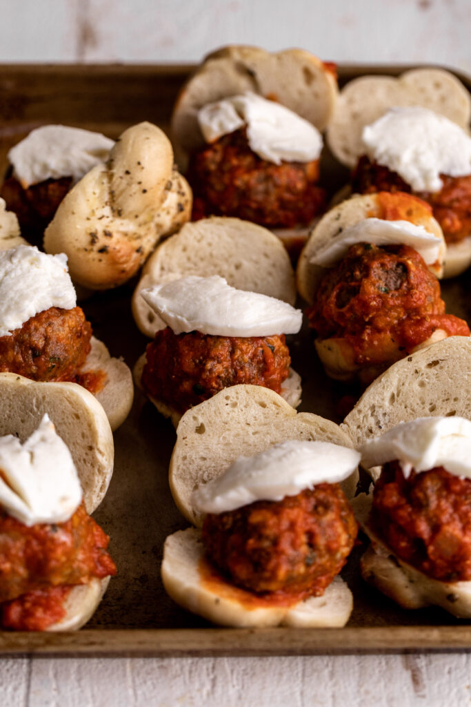 assembled Garlic Knot Meatball Sliders with tomato sauce and melted mozzarella cheese