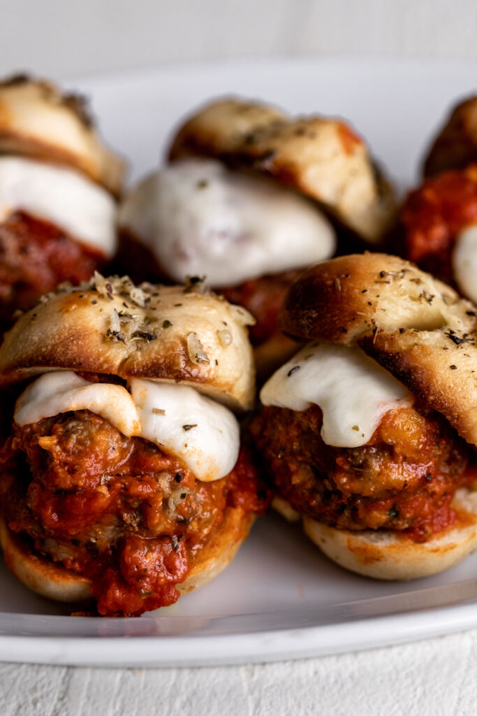 Garlic Knot Meatball Sliders with tomato sauce and melted mozzarella cheese