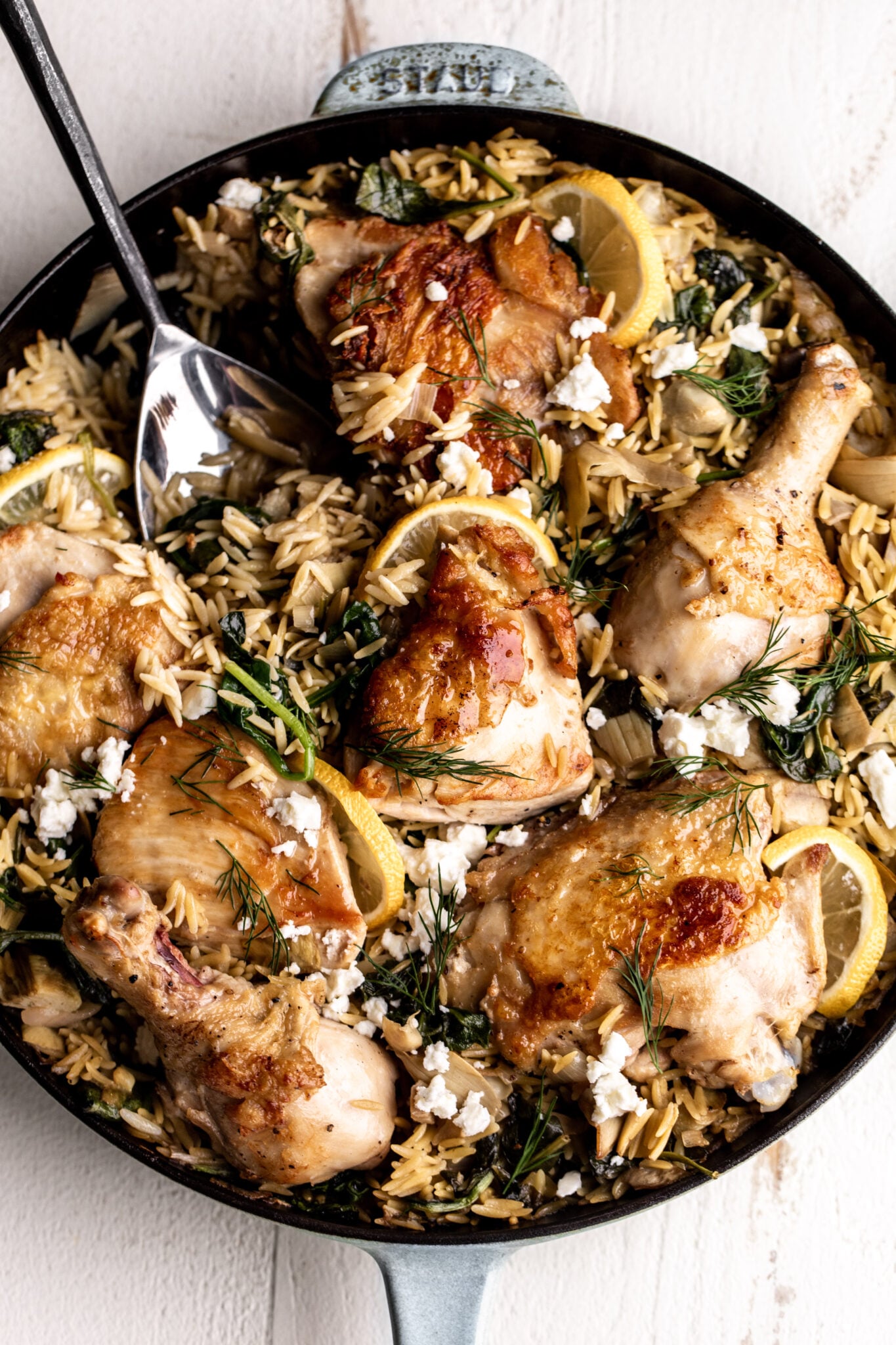 spinach and artichoke and orzo bake in staub pan.