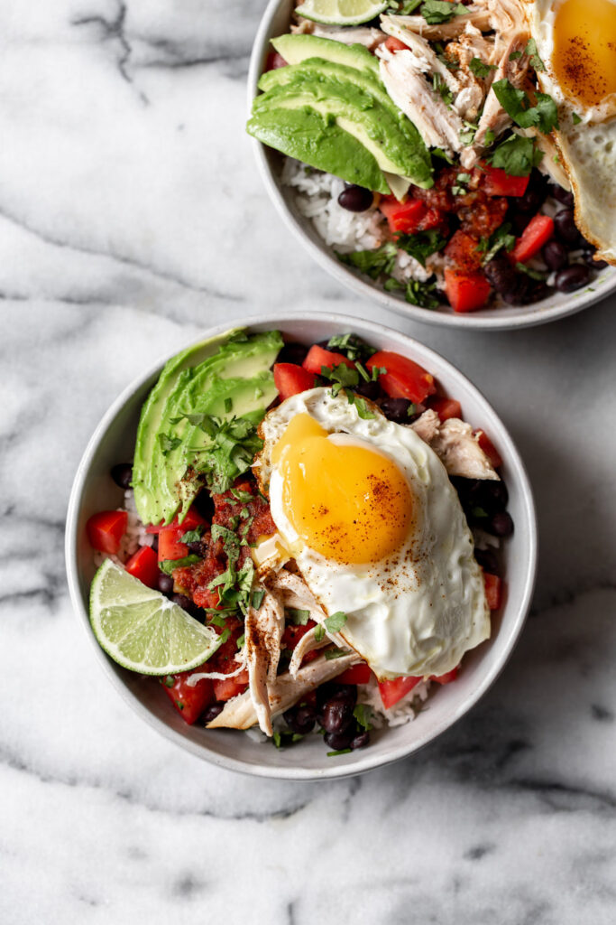 shredded chicken rice bowl topped with black beans, pico and sunnyside up fried egg