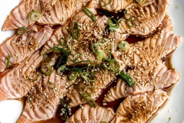 slices of seared salmon sushi (aburi) with ponzu and green onion.