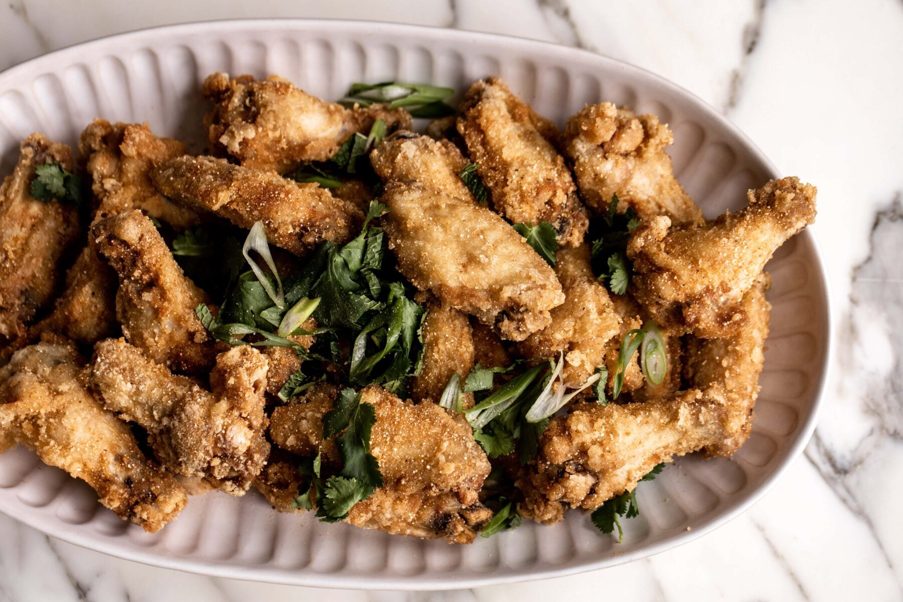 Thai chicken wings with herbs on platter.