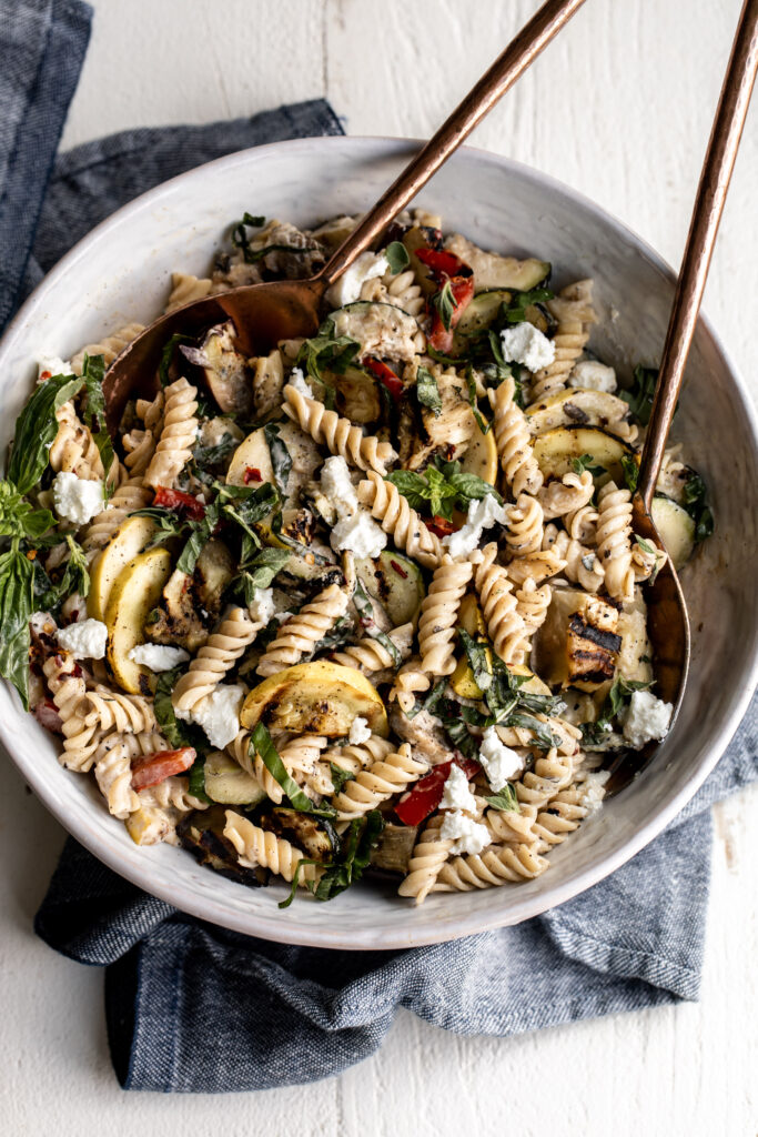 creamy pasta salad in white bowl with grilled zucchini, squash and eggplant 