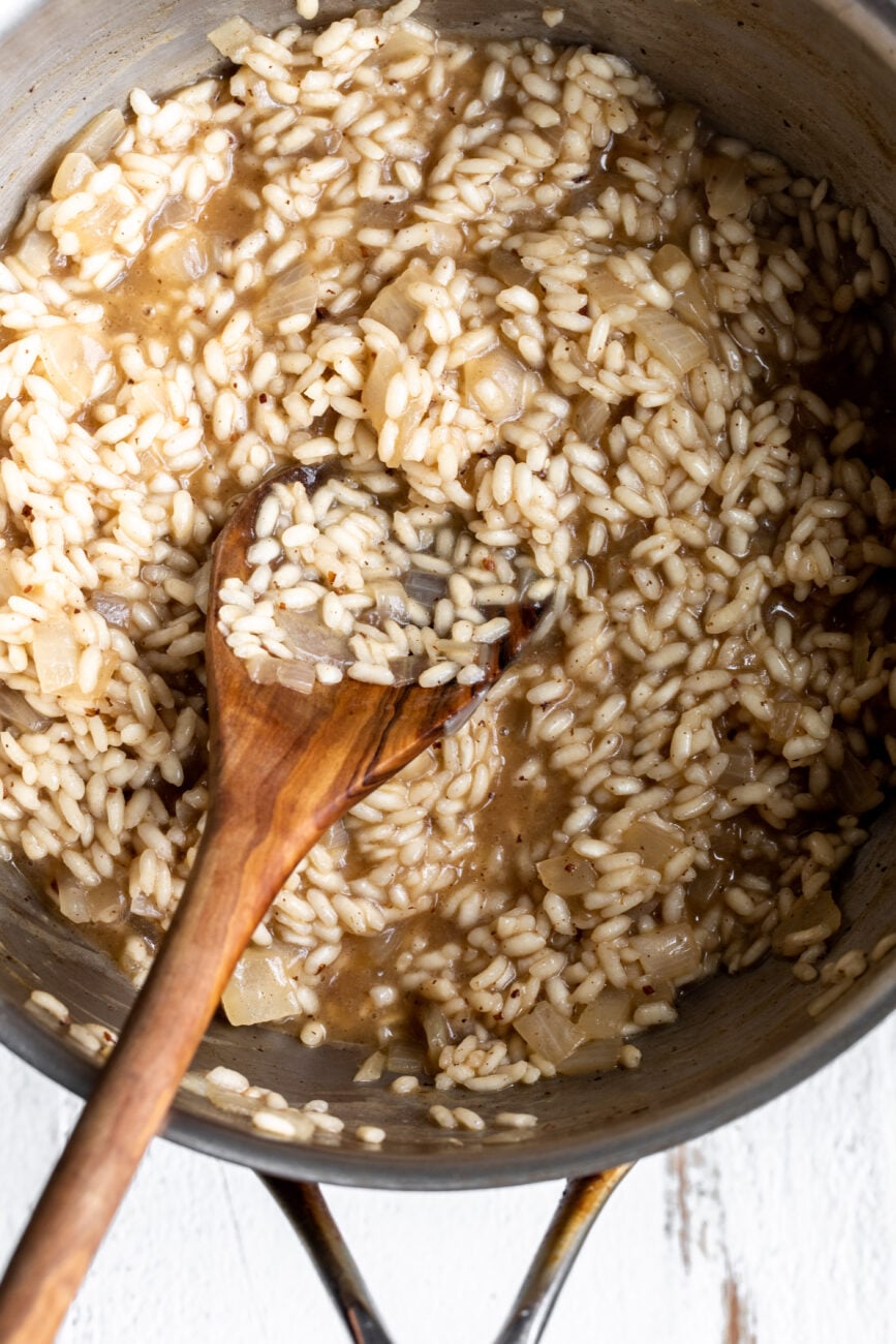 risotto cooked in pan with wooden spoon.
