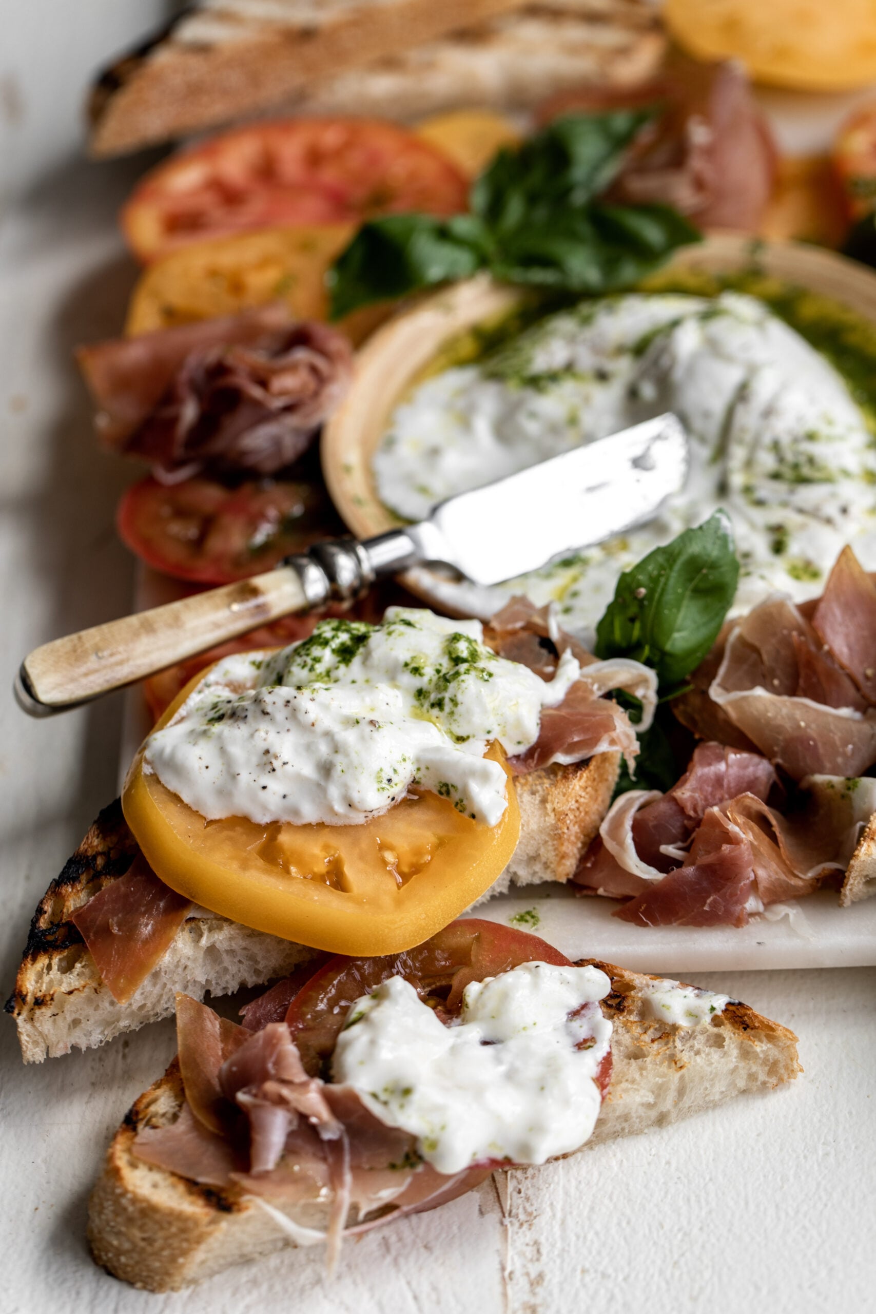 Heirloom Tomato, Prosciutto & Burrata with Garlic-Basil Oil cut with knife.