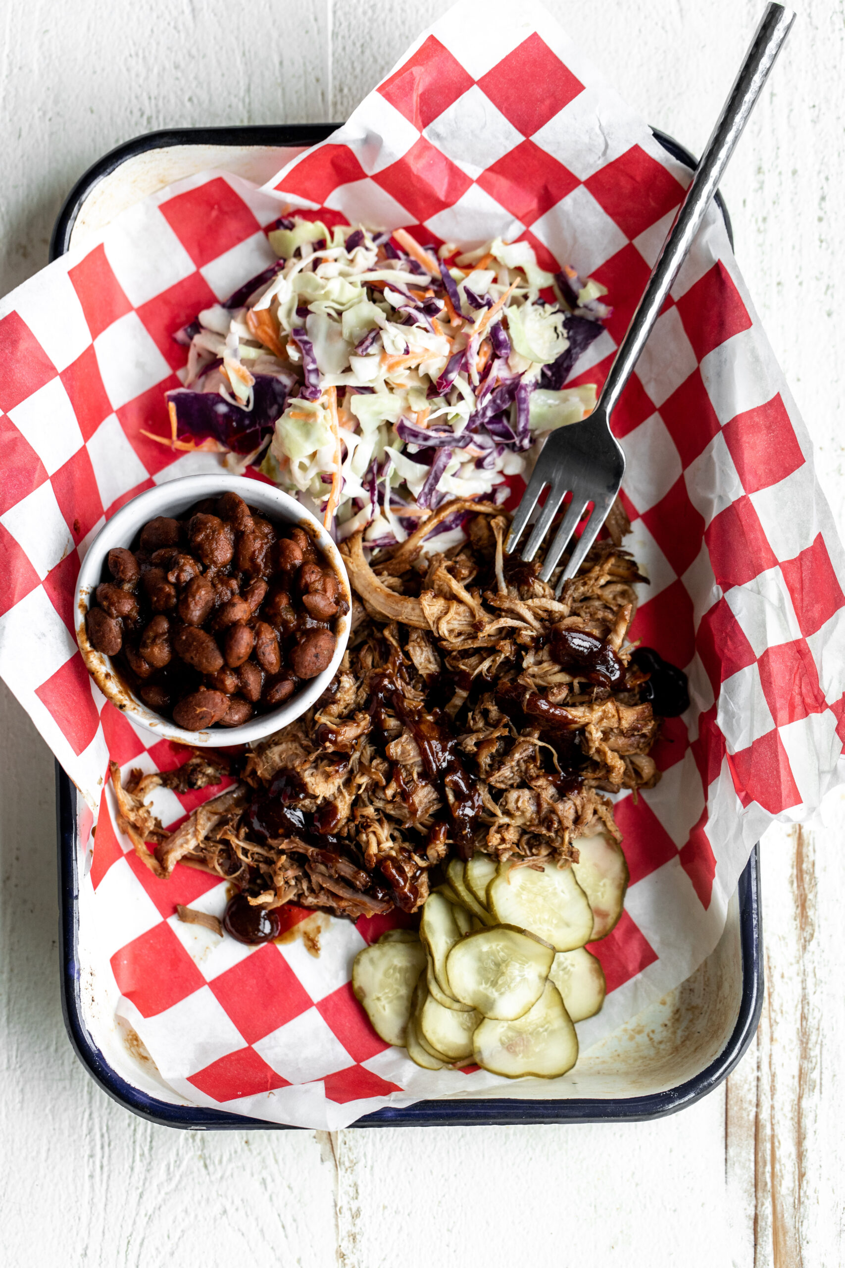 braised pulled pork on a BBQ platter with baked beans coleslaw and pickles