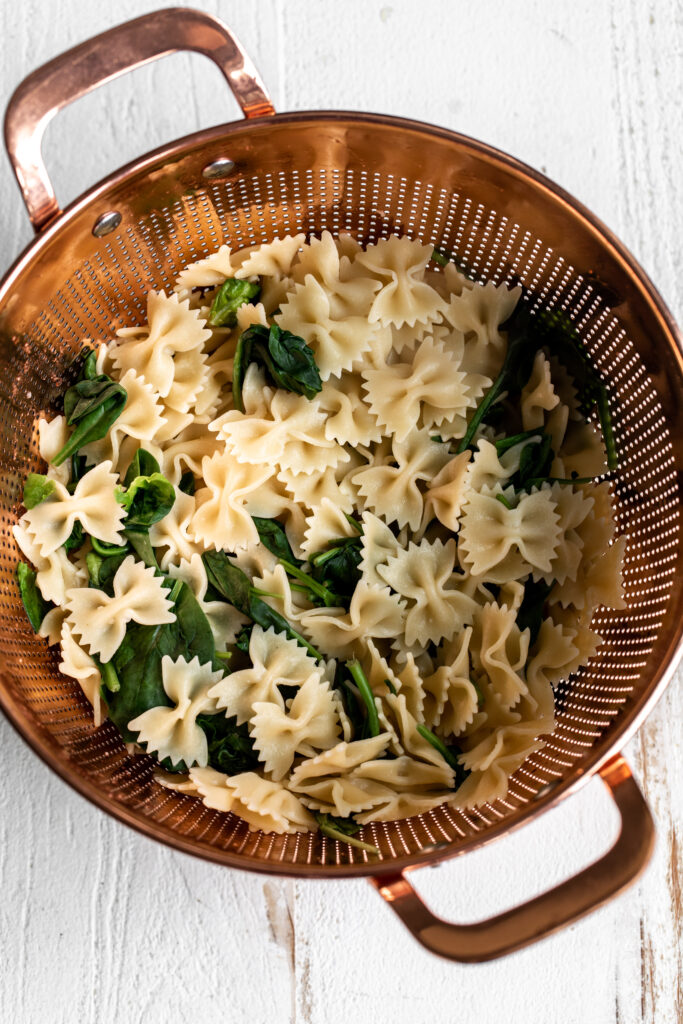 draining pasta and spinach for Pesto Pasta Salad Recipe 
