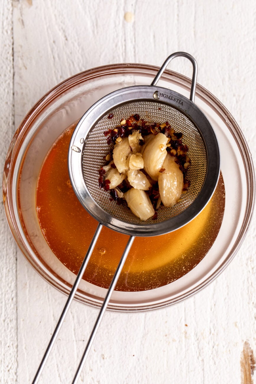 straining the hot honey sauce.