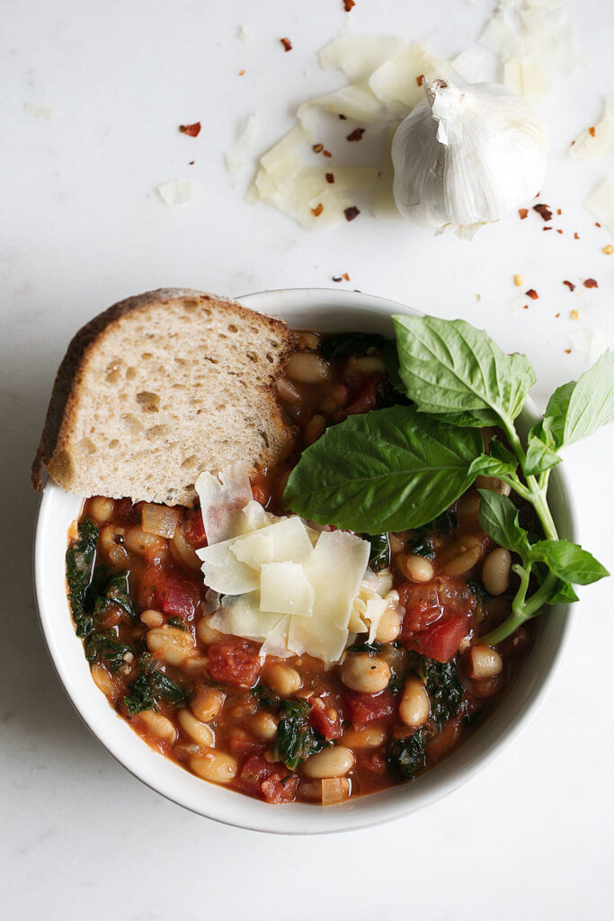 white bean and kale tomato soup with bread slice and basil