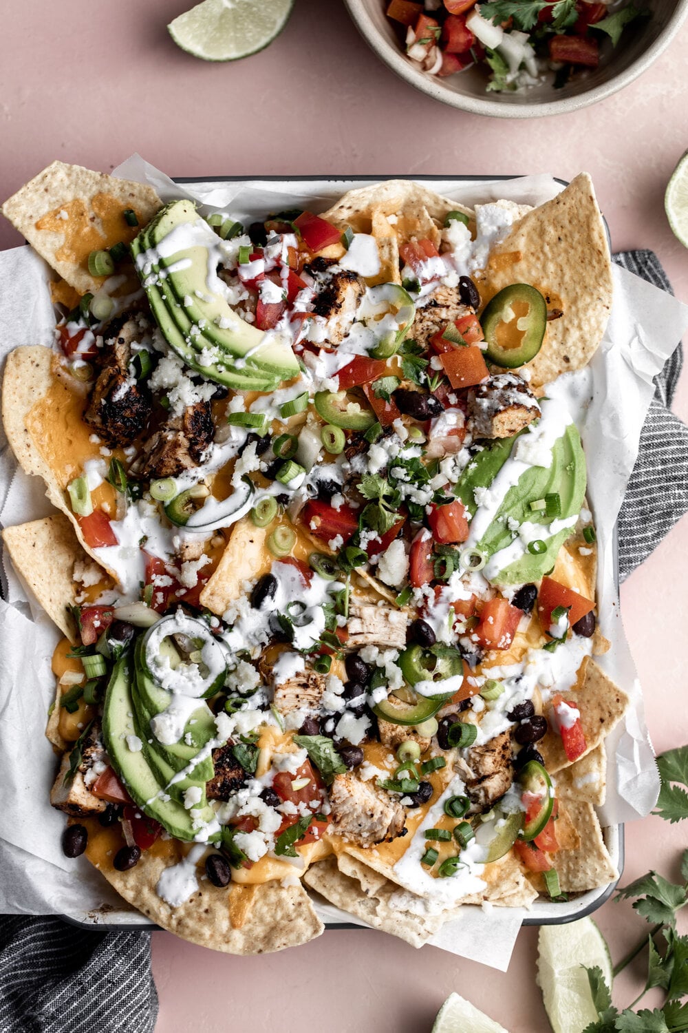 loaded three cheese chicken nachos with avocado, olives, beans and a drizzle of sour cream.