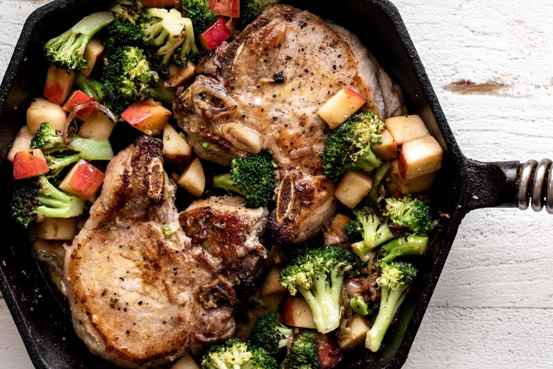 Pan-Seared Miso Butter Pork Chops with Sautéed Broccoli and Apples in cast iron.