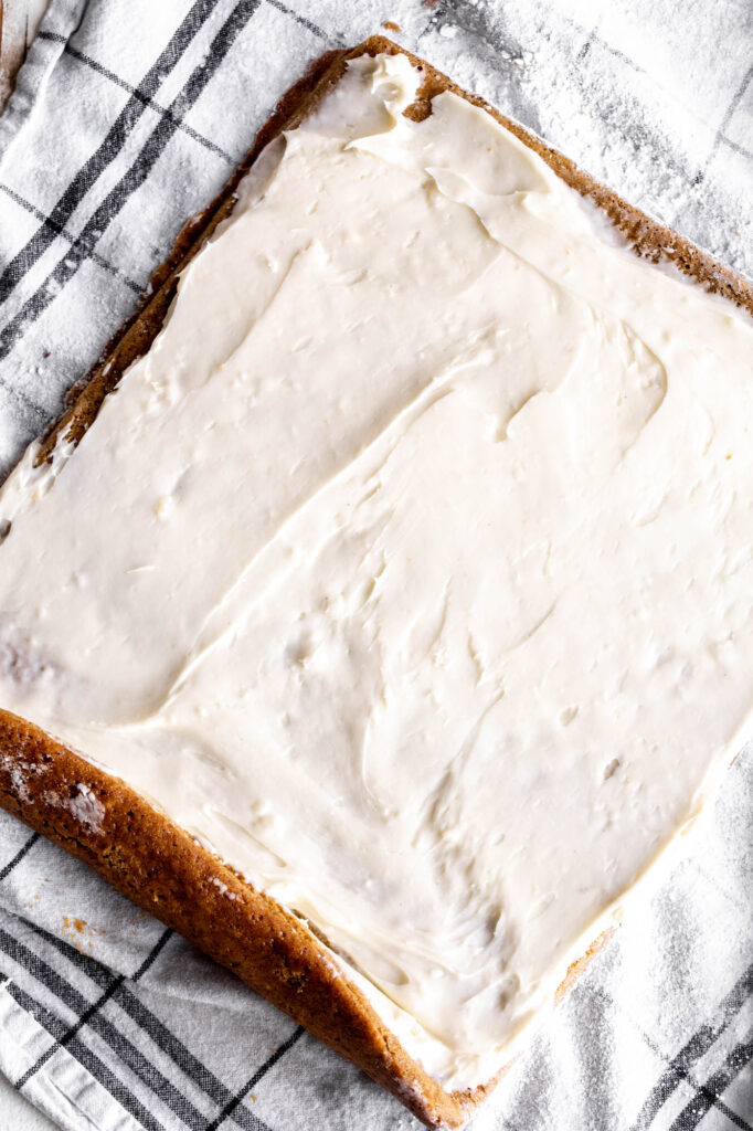 cream cheese frosting spread over spiced pumpkin sponge cake