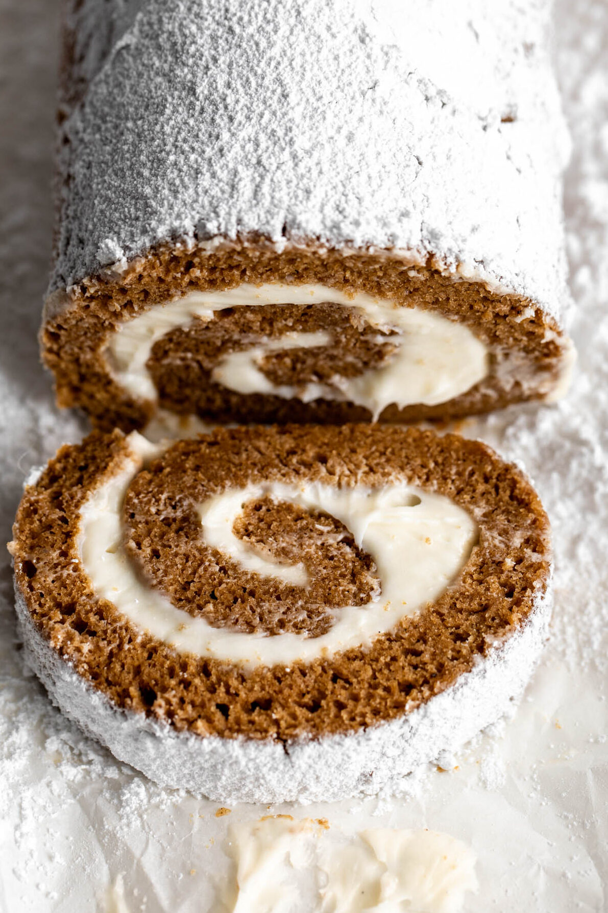 closeup photo of pumpkin roll with cream cheese frosting garnished with powdered sugar
