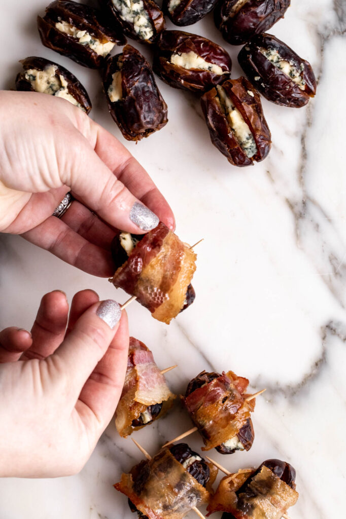 person wrapping cheese-filled dates with bacon