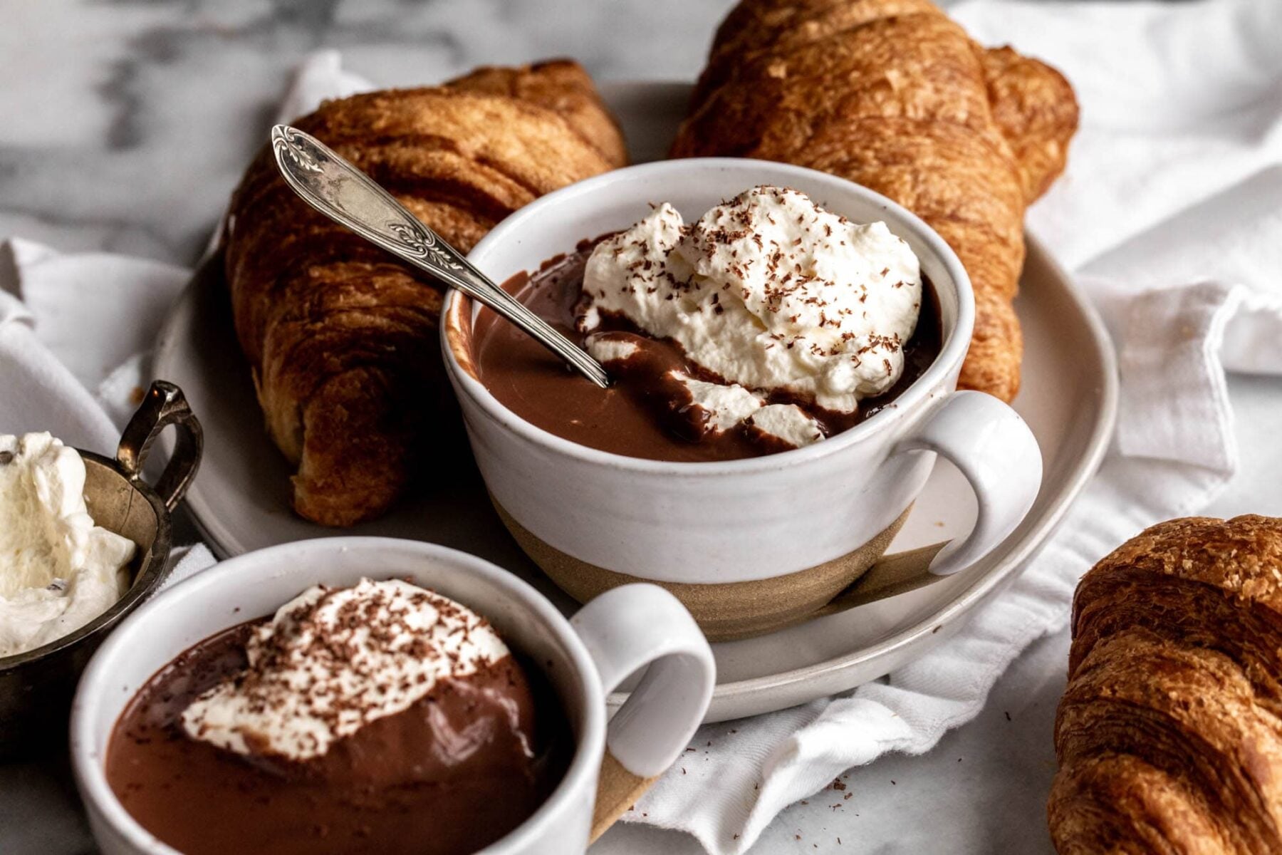 French Hot Chocolate in a mug topped with whipped cream and chocolate shavings.