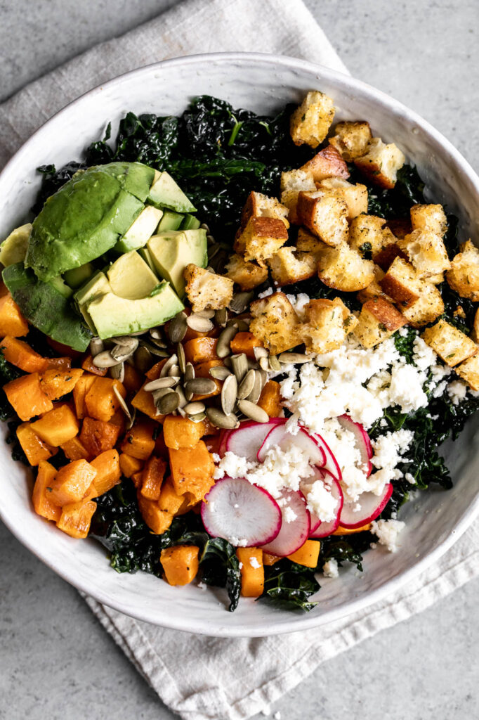 mexican-inspired kale salad with roasted squash in a white bowl