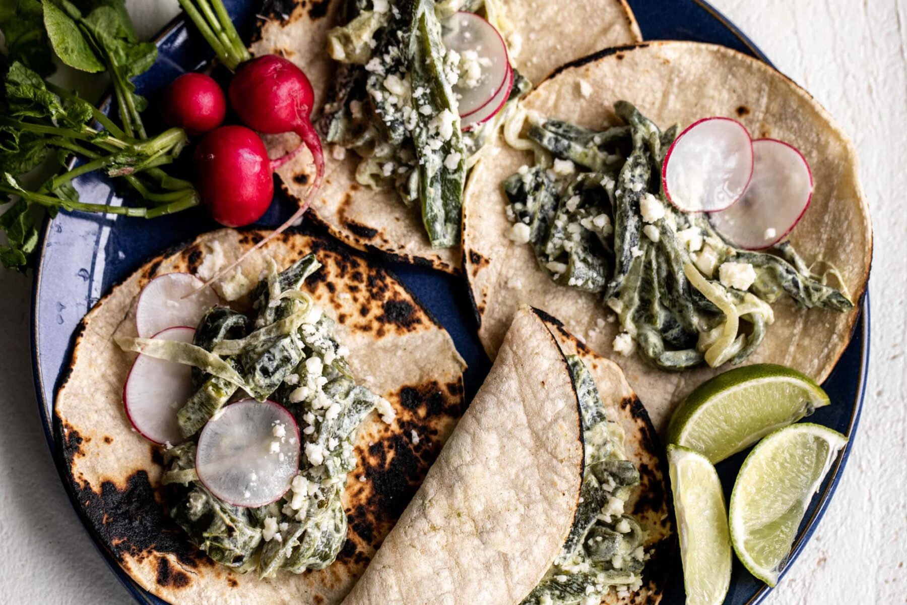 Creamy poblano tacos on corn tortillas with sliced radish.