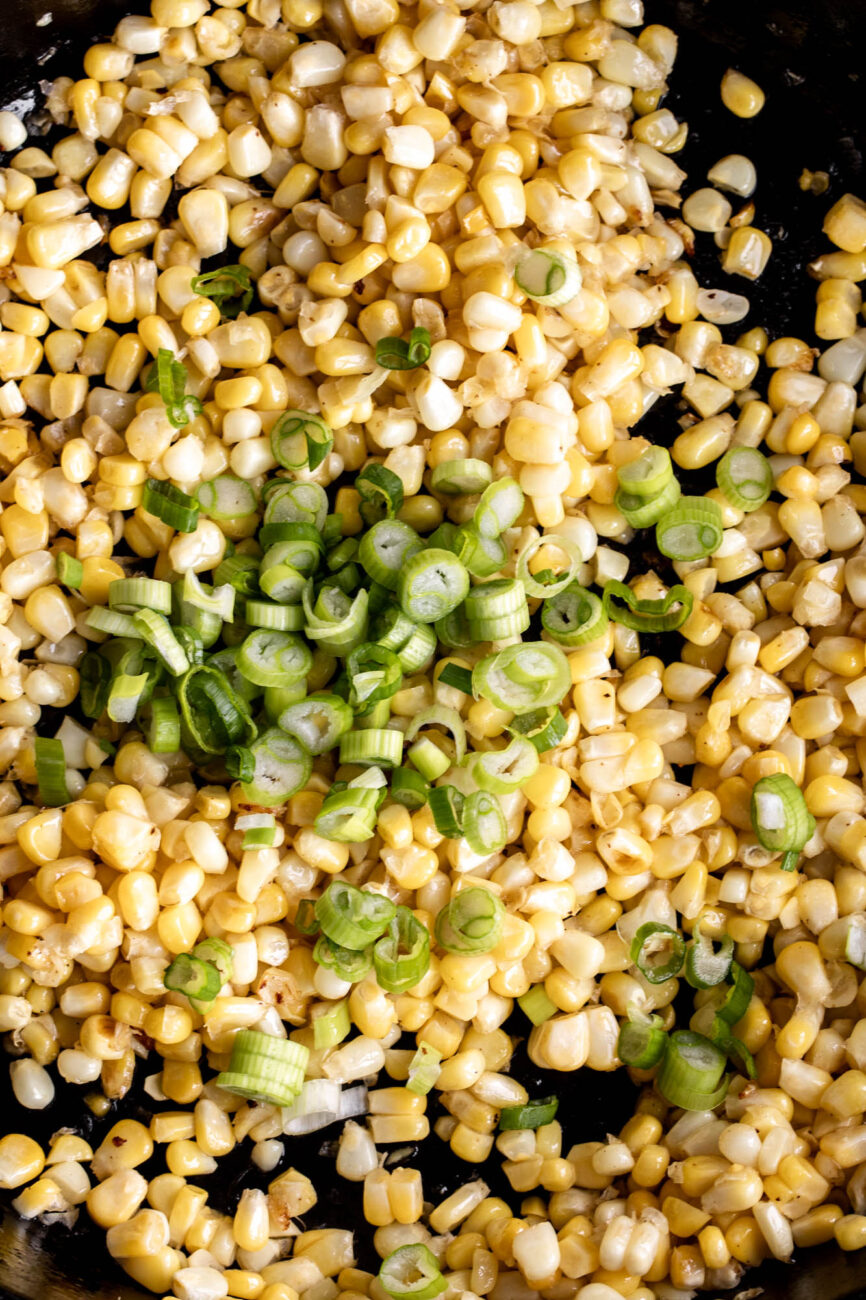 sautéed corn with sliced green onions in cast iron skillet.
