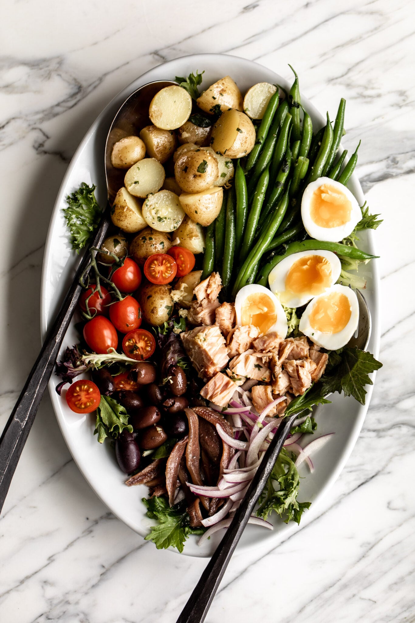 Niçoise Salad with tongs.