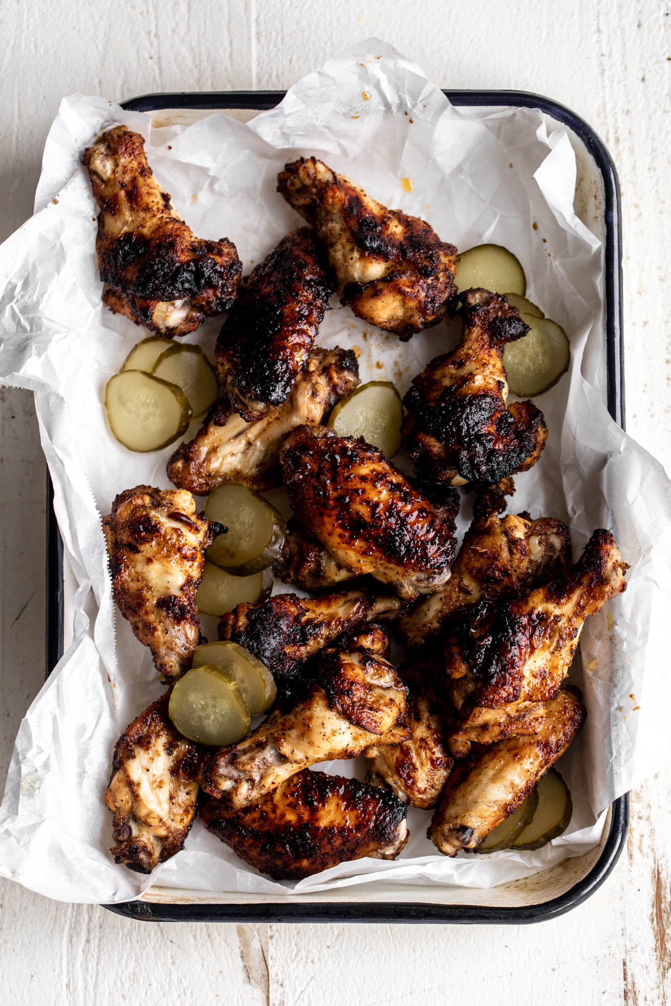 pickleback chicken wings with pickle slices on baking sheet lined with parchment paper.