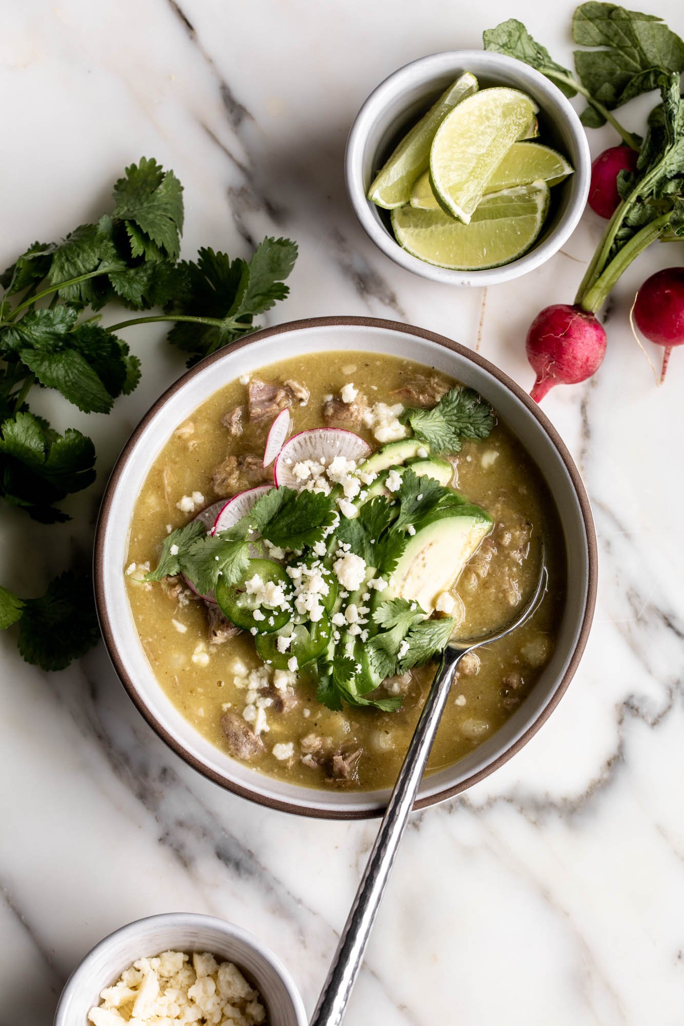 pork pozole verde with sliced avocado, radish, cilantro, jalapeño slices.