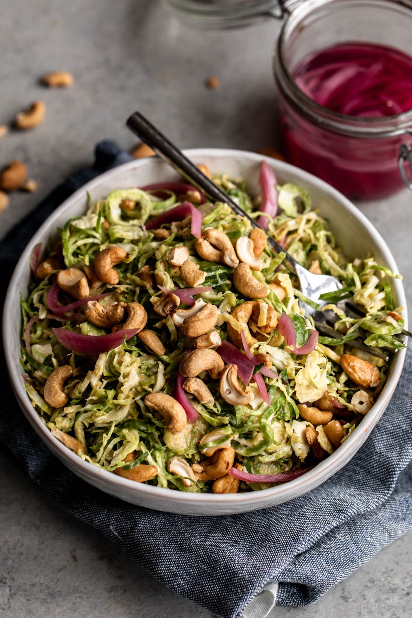 shredded Brussels sprouts in miso dressing with pickled onion and whole cashews.