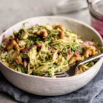 shredded Brussels sprouts tossed in a creamy miso dressing with pickled onion and roasted cashews.