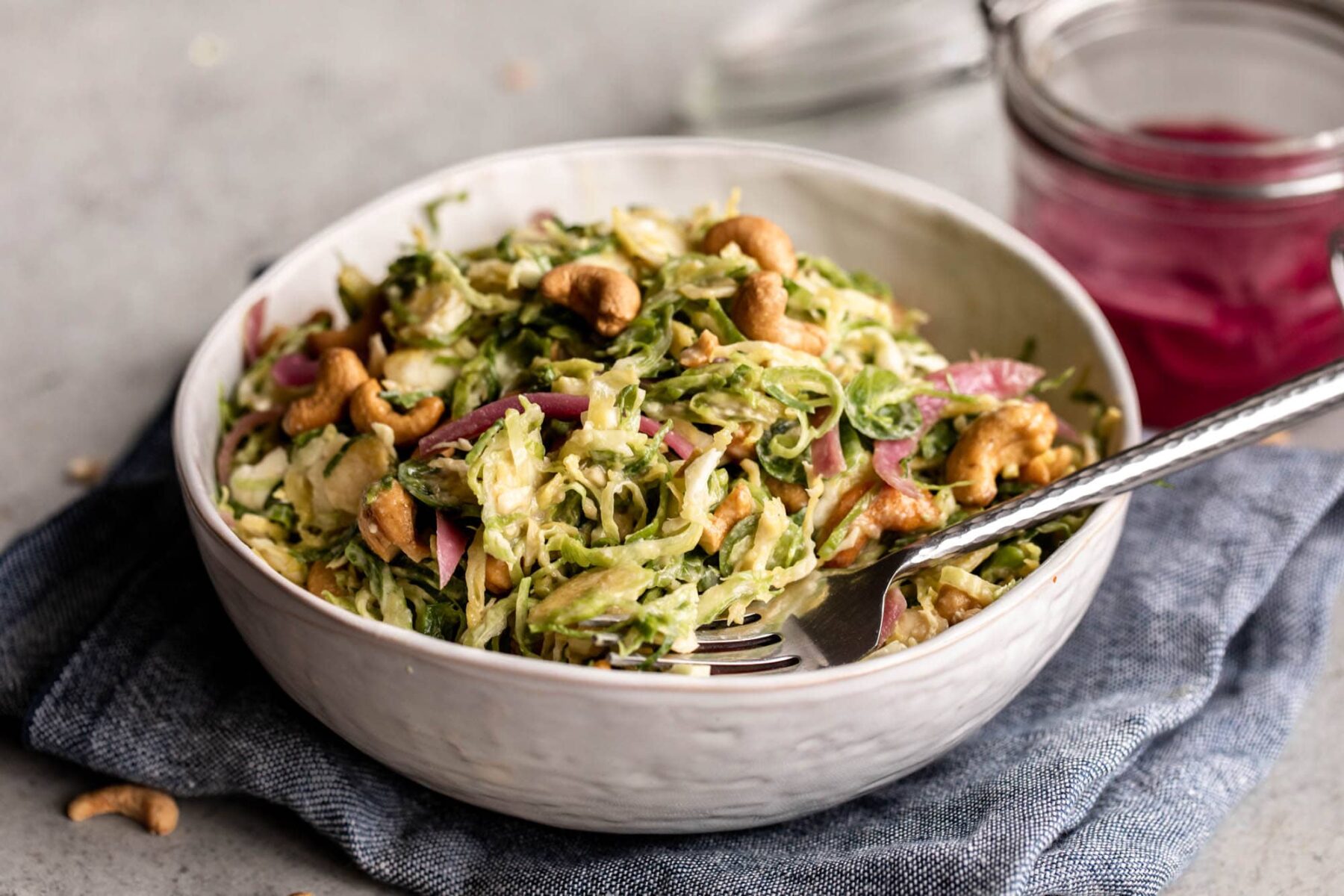 shredded Brussels sprouts tossed in a creamy miso dressing with pickled onion and roasted cashews.