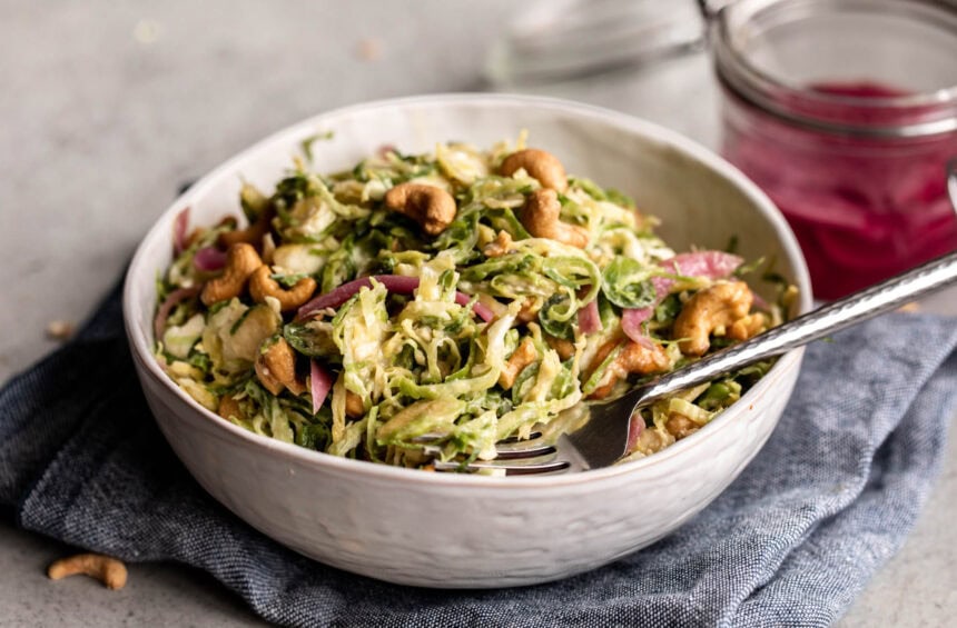 shredded Brussels sprouts tossed in a creamy miso dressing with pickled onion and roasted cashews.