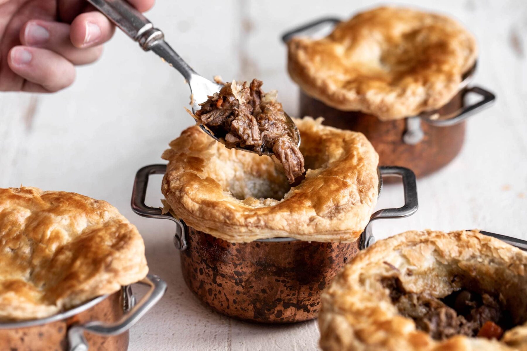 stout braised steak and mushroom pot pies in copper pots.