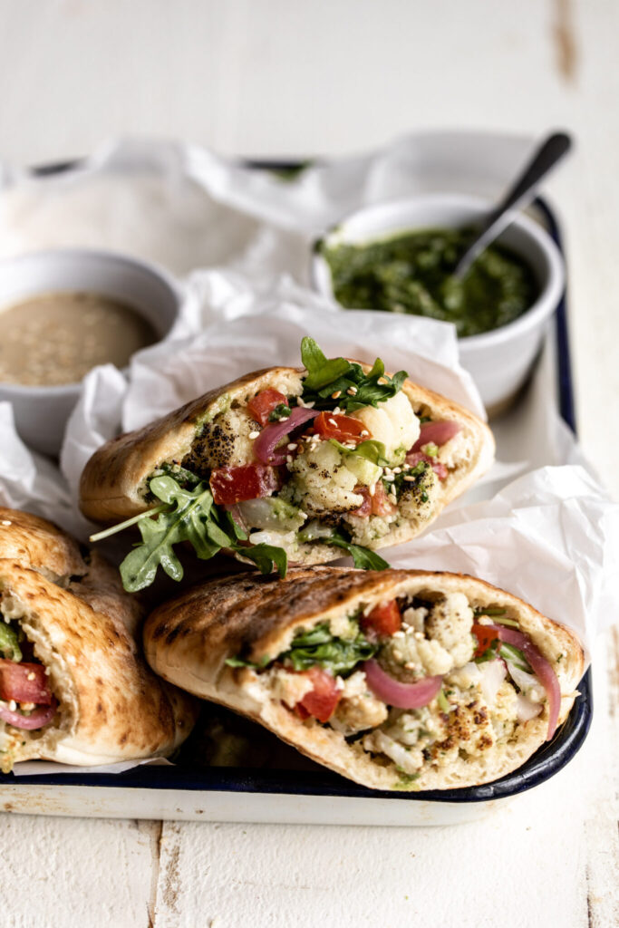 roasted cauliflower pita with arugula and pickled onions on baking sheet.