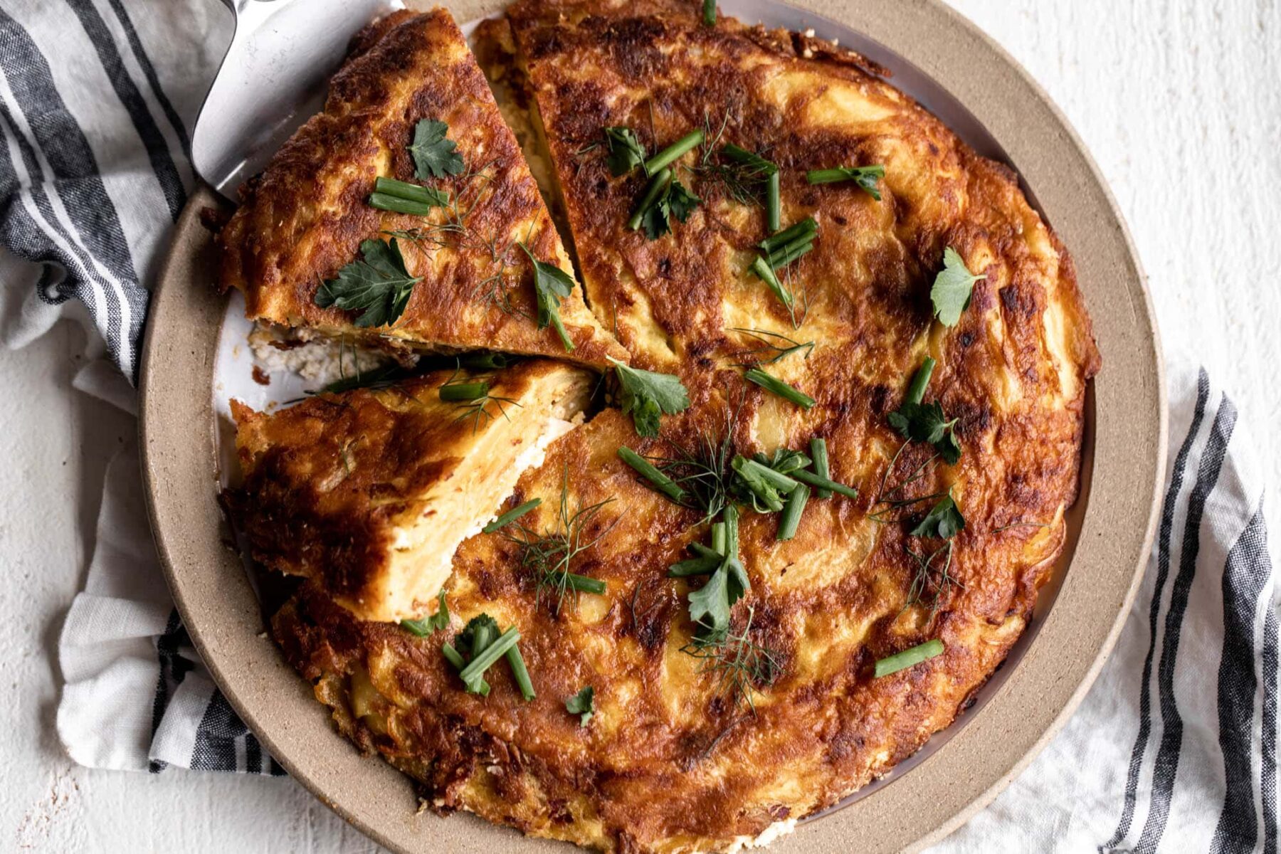spanish omelette with chorizo cut into slices on plate.