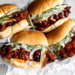 buffalo fried chicken sandwiches with blue cheese celery slaw on white parchment paper.