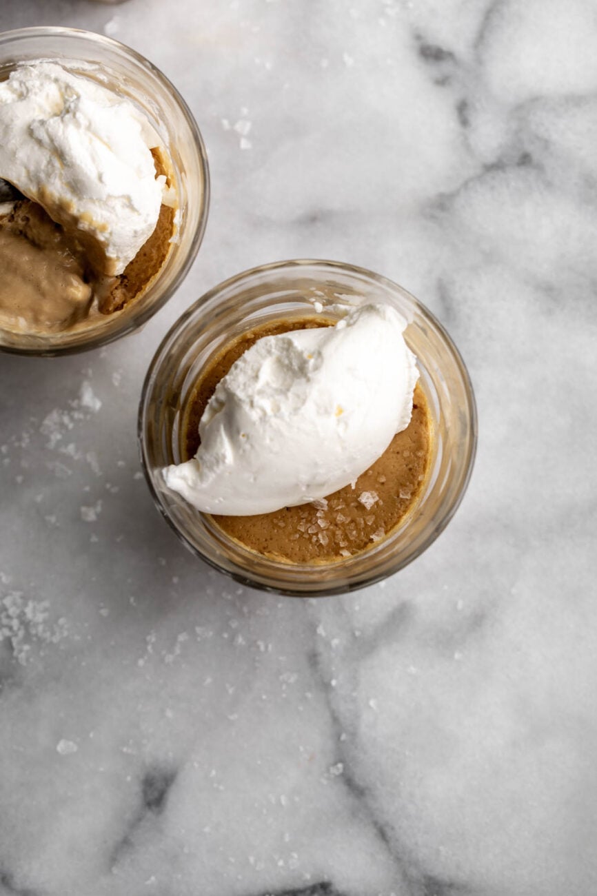 Salted Butterscotch Pots de Crème in small glass jars with whipped cream.