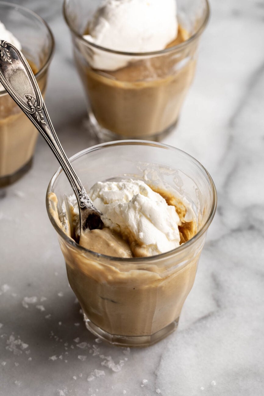 individual glass jar salted butterscotch pot de creme eating with spoon.
